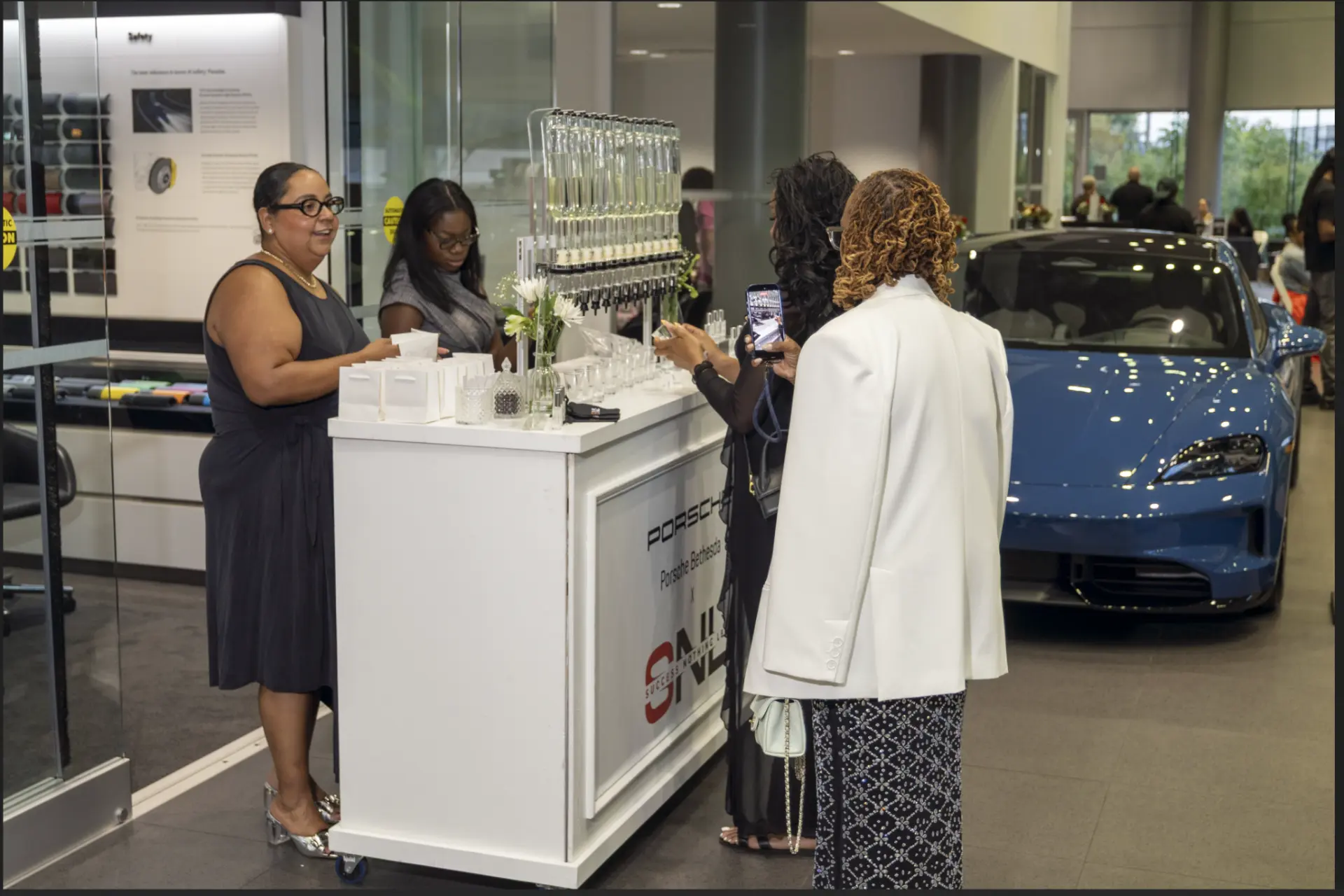 Guests at the Porsche Bethesda x Success Nothing Less scent activation with a Porsche in the background