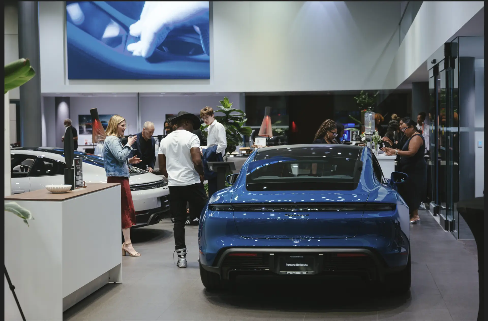 Guests in the Porsche Bethesda showroom among luxury vehicles